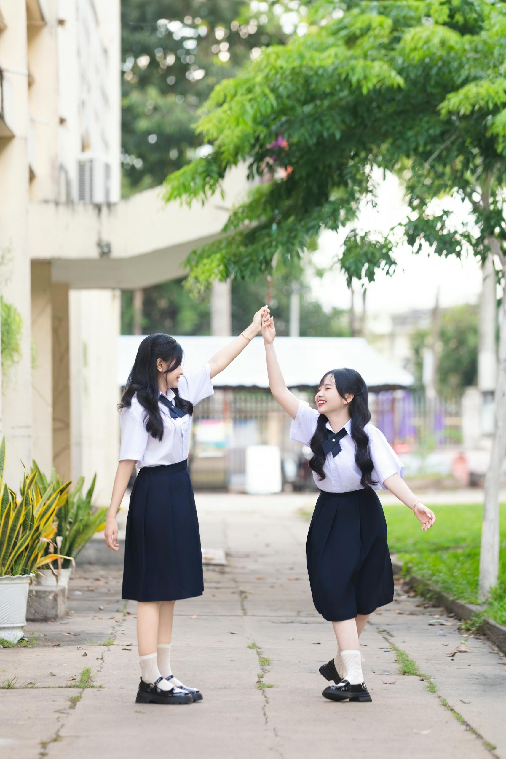 Two students in school uniforms enjoying a playful moment outdoors, celebrating friendship.
